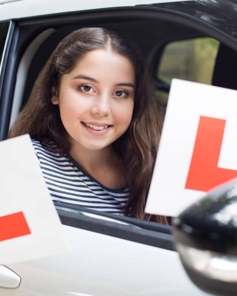 Portrait Of Teenage Girl Passing Driving Exam Holding Learner Plates